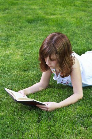 Young beautiful girl reading a book outdoorの写真素材