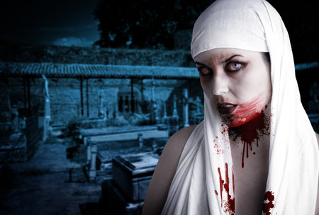 Female vampire with blood stains in a cemetery. Gothic Image halloweenの写真素材