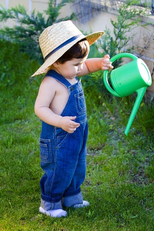 little baby gardener with hat watering the plantsの写真素材