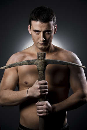 Topless construction worker with pick axe  over grey backgroundの写真素材