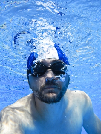 Man swimming with glasses underwater in poolの写真素材