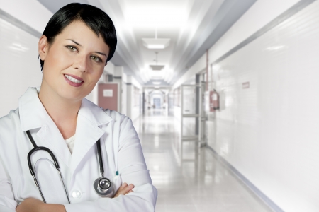 brunette female doctor on duty at white hospital corridorの写真素材