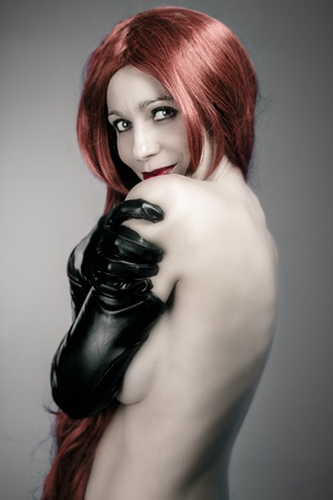 beautiful woman with red hair in sexy evening dress against dark backgroundの写真素材