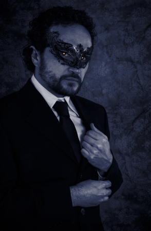 Vampire masked mystery man and elegant black suit over vintage backgroundの写真素材