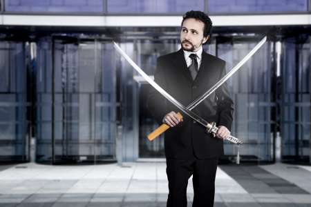 Businessman with two Japanese swords at the entrance of an office buildingの写真素材