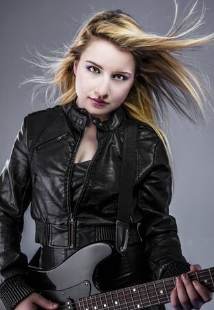 Blonde, Beautiful young woman dressed in black rock with electric guitarの写真素材