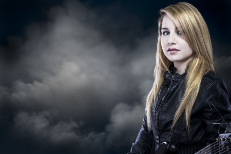 beautiful young blond woman with leather jacket and guitarの写真素材