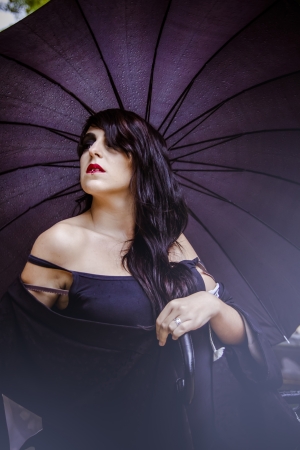 pretty young woman with black umbrella, under autumn rain in a palace parkのeditorial素材