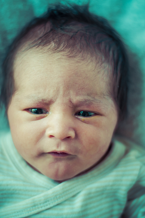 Newborn peacefully sleeping, picture of a baby curled up sleeping on a blanketの写真素材
