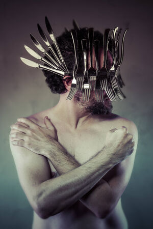 Nude man with helmet made ââwith forks and knives, artistic conceptの写真素材