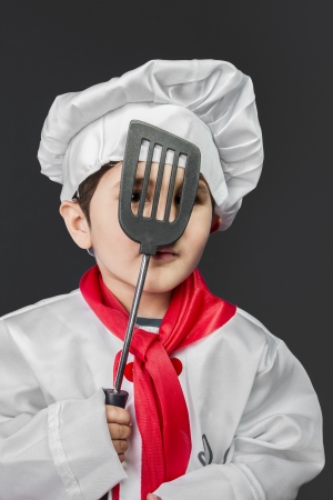 Cooking, Little boy preparing healthy food on kitchen over grey background, cook hatの写真素材