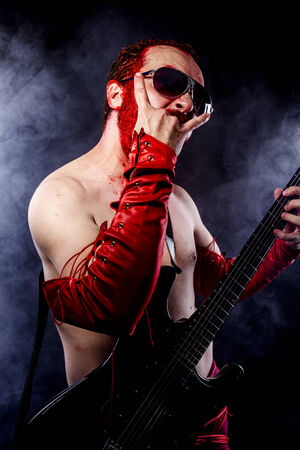 Playing, guitarist with electric guitar black, wearing face paint and red leatherの写真素材