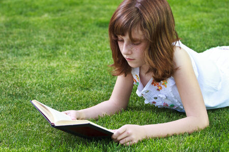Park.Young beautiful girl reading a book outdoorの写真素材