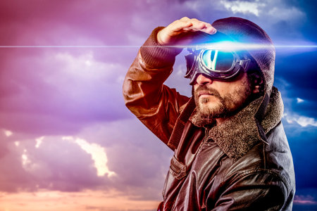 man dressed as pilot in helmet on clouds background. Vintage pilot (aviator) concept