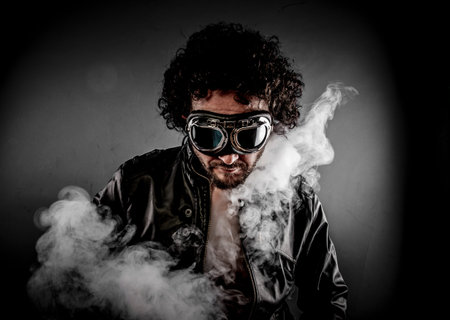 Sensual male biker with sunglasses era dressed Leather jacket, huge smoke over dark backgroundの写真素材