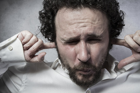Businessman covering his ears, man in white shirt with funny expressionsの写真素材