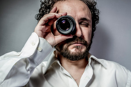 photographer with lens, man with intense expression, white shirtの写真素材