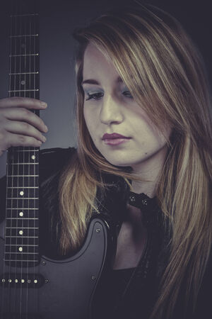 Heavy, Beautiful blond girl with black electric guitarの写真素材
