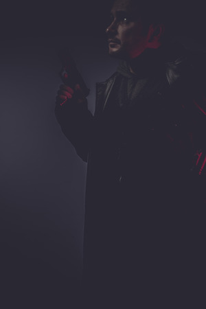 portrait of stylish man with long leather jacket, gun armedの写真素材