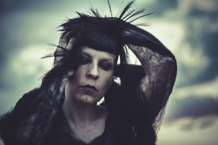 sad brunette woman dressed with black spider web, sunsetの写真素材