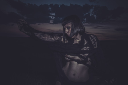 depressed brunette woman dressed with black spider web, sunsetの写真素材