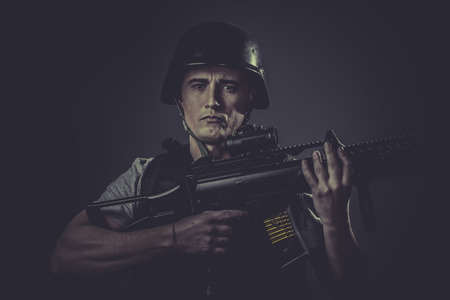 Recreation, paintball sport player wearing protective helmet aiming pistol ,black armor and machine gunの写真素材