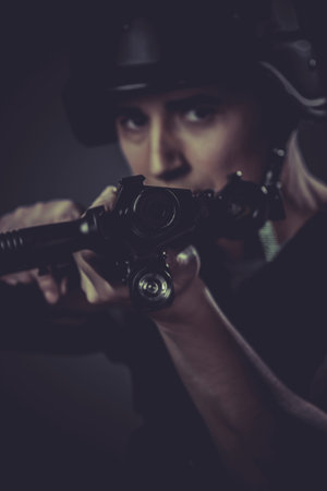 Gunfire, paintball sport player wearing protective helmet aiming pistol ,black armor and machine gun