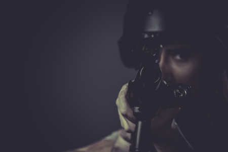 Gunfire, paintball sport player wearing protective helmet aiming pistol ,black armor and machine gunの写真素材