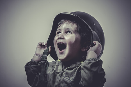 uniform, fun and funny child dressed in military cap, playing war gamesの写真素材