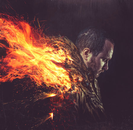 fallen angel, jacket man with golden feathers on the wings and fireの写真素材