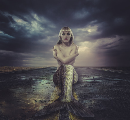 naked mermaid sitting on a deserted roadの写真素材