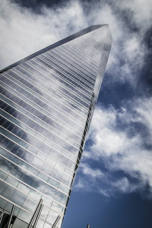 finance, skyscraper with glass facade and clouds reflected in windowsのeditorial素材
