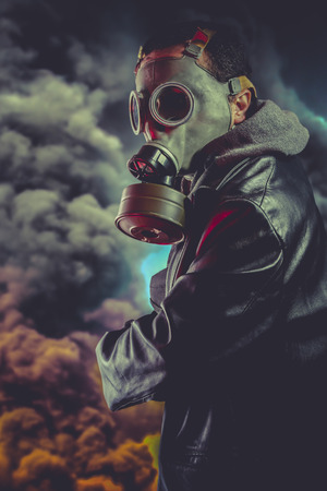 Armed man with gas mask over explosion backgroundの写真素材