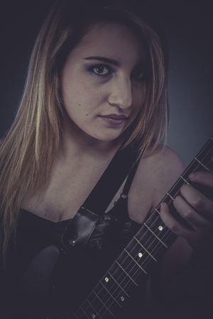 Heavy musician, Beautiful blonde with black electric guitarの写真素材