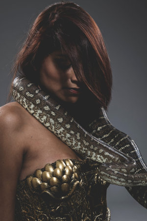 Sensual tattooed woman with big snake and iron corset