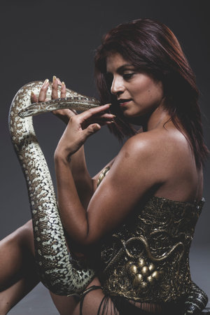 Model, Sensual tattooed woman with big snake and iron corset