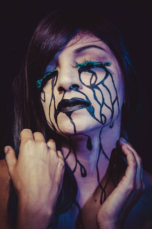 concept, crying woman with tears and makeup dark lightの写真素材