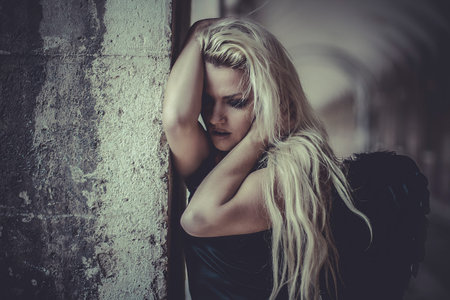 Sensual fallen angel, beautiful blonde woman with black wings and tight dressの写真素材