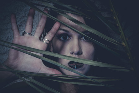 Sensual young girl hidden behind the branches of a treeの写真素材