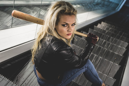 Urban beautiful blonde with a baseball bat in escalators