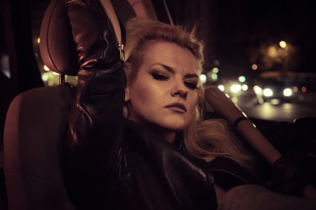 aggressive look blonde driving a car at night in the cityの写真素材