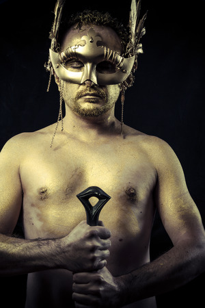 Warrior with helmet and sword with his body painted gold dustの写真素材