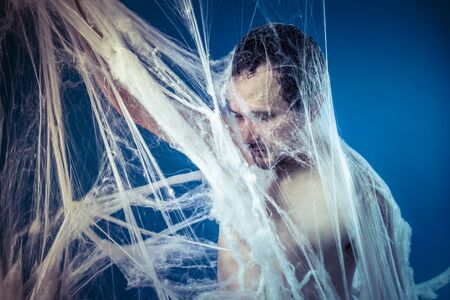 Tangled, naked man trapped in a huge spider webの写真素材