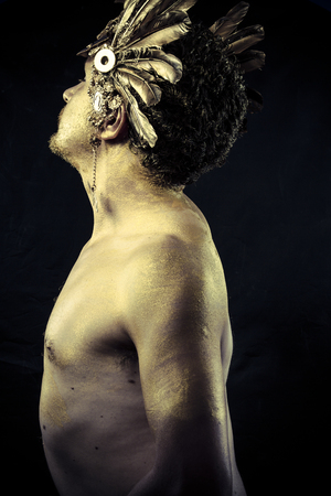Warrior with helmet and sword with his body painted gold dustの写真素材