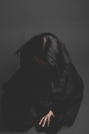 gothic dark woman with large black cloth on gray background, Sadnessの写真素材
