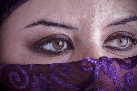 Beautiful arabic woman with traditional veil on her face, intense lookの写真素材