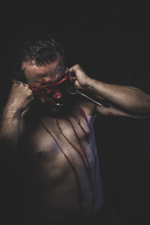 naked man with blindfold soaked in bloodの写真素材