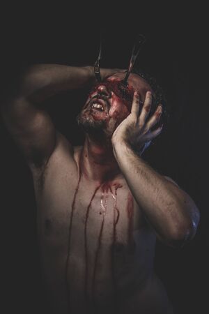 Sinister, naked man with blindfold soaked in bloodの写真素材