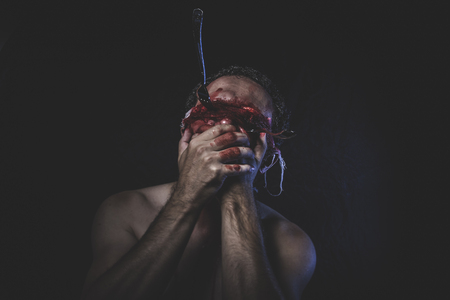 naked man with blindfold soaked in bloodの写真素材