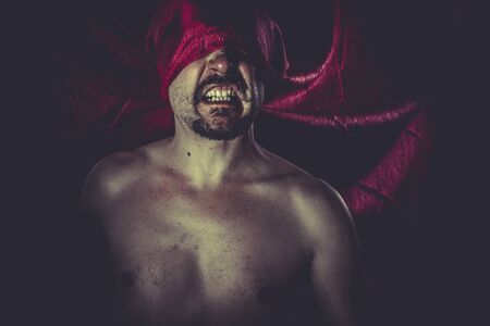 Halloween, naked man on large red cloth over his eyesの写真素材